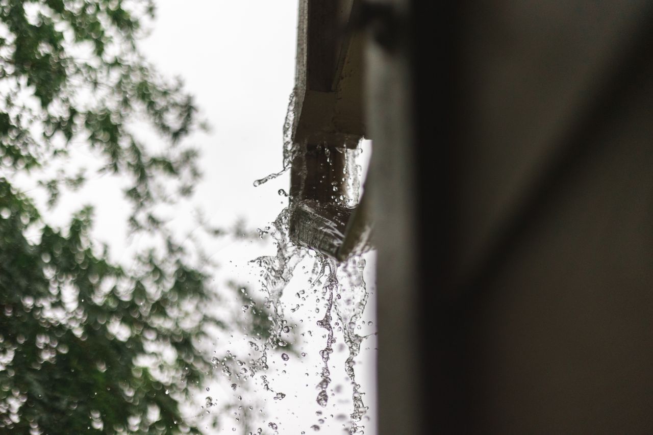 Home Close-up of rainwater pouring from a gutter, captured during a rainfall in Houston.